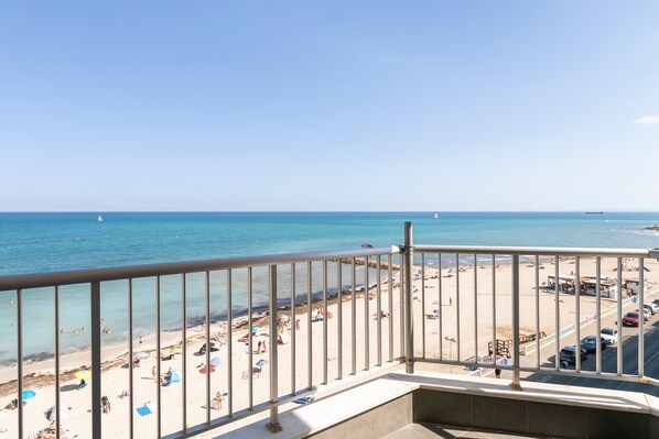 A balcony with a view of a beach and the sea.