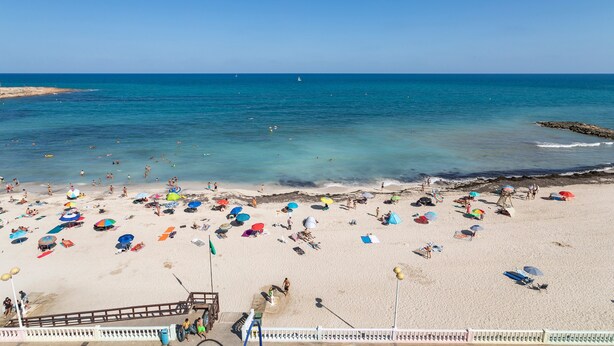 A beach with numerous umbrellas and people.