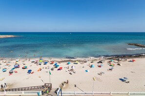 A beach with numerous umbrellas and people.