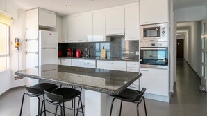 A modern kitchen with white cabinets, a granite countertop, and built-in appliances including a microwave and oven.