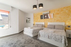 A bedroom with two beds, a window, an air conditioning unit, and a ceiling light fixture.