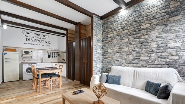 Un salon avec un mur en pierre, un canapé blanc et une table à manger en bois.