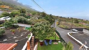 Un quartier résidentiel avec une allée pavée, un grand arbre et une voiture blanche garée dans la rue.