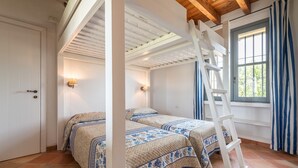 Une chambre avec deux lits, une échelle, une fenêtre avec des rideaux et une porte.