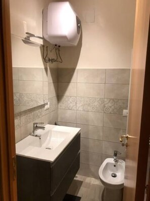Een badkamer met een wastafel, spiegel en toilet met douchefunctie.