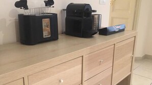 Een kitchenette met een koffiezetapparaat, een broodrooster en een prullenbak.