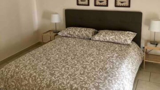 Een slaapkamer met een bed, twee nachtkastjes en drie wandklokken.