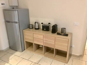 Eine Küche mit Kühlschrank, einer Holzküche mit Schubladen und einer Arbeitsplatte mit verschiedenen Geräten.