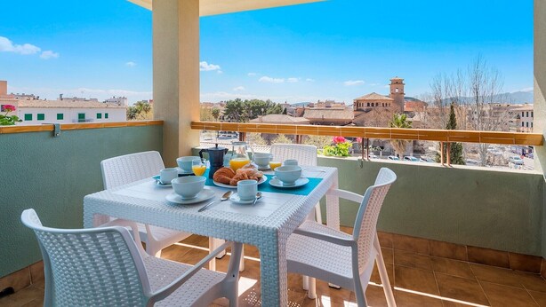Un balcon avec une table dressée pour le petit-déjeuner, offrant une vue sur le paysage urbain.