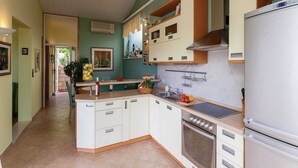 A kitchen with white cabinets, a built-in oven, and a refrigerator. - Apartments Ankora (Dubrovnik)