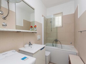 A bathroom with a sink, mirror, shower, and toilet. - Apartments Ankora (Dubrovnik)