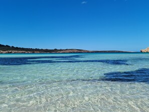 A clear coastal view with calm waters and rocky terrain.