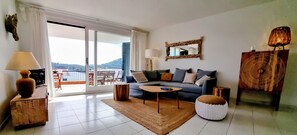Una sala de estar con sofá, mesa de centro y vistas a una terraza exterior por medio de un ventanal corredero.