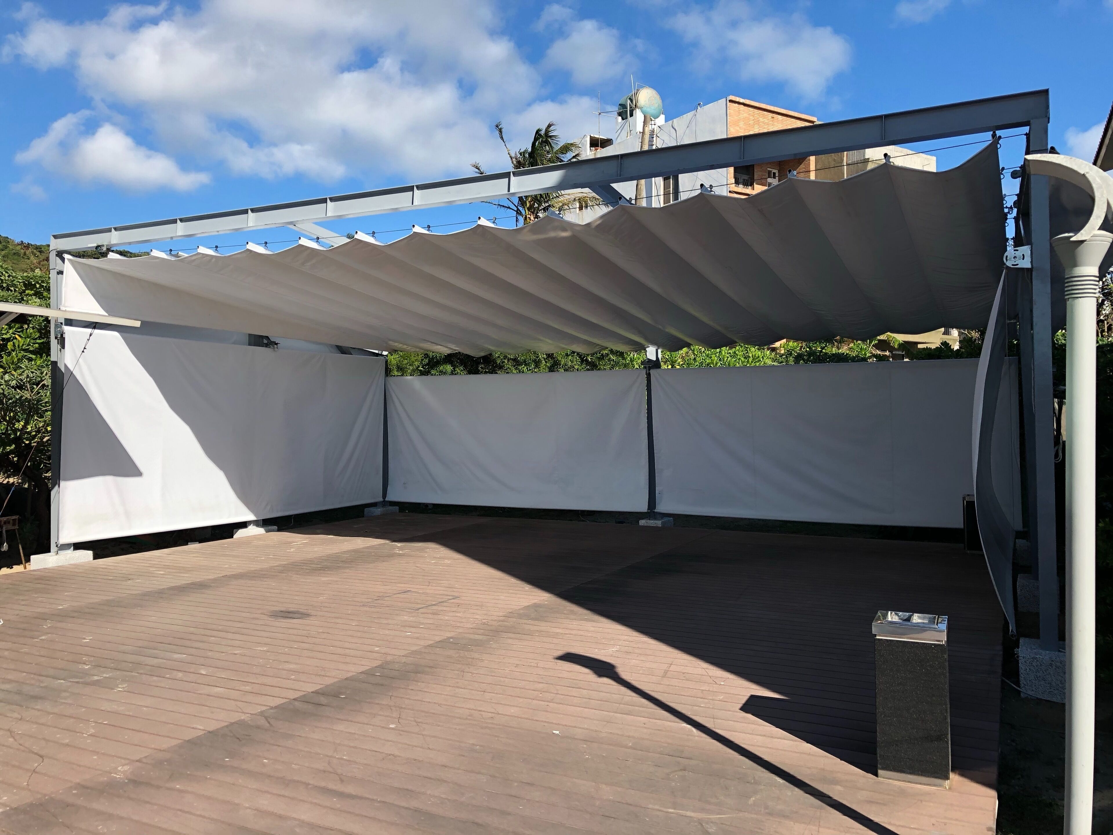 An outdoor patio area with a white canopy, a brick floor, and a metal railing.