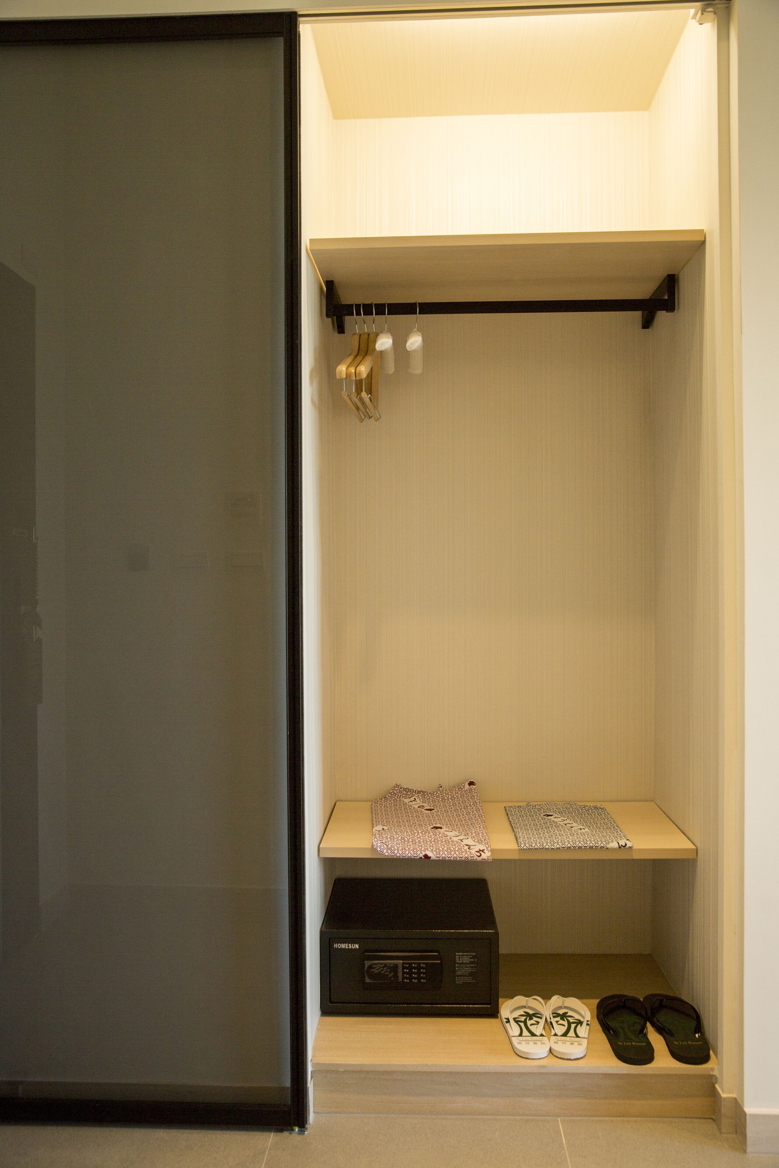 A walk-in closet with a shelf holding shoes, a box, and a hanging garment.