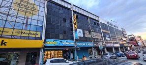 A building with multiple storefronts, including a bank, an optometry clinic, and a pharmacy. - OYO 90461 Melawati Times Inn (Taman Melawati)