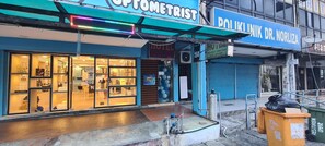 A storefront with a sign for 'Optometrist' and another for 'Poliklinik Dr. Norliza'. - OYO 90461 Melawati Times Inn (Taman Melawati)