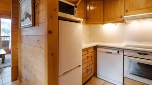 A wooden cabin interior with a refrigerator, dishwasher, oven, and wooden cabinets.