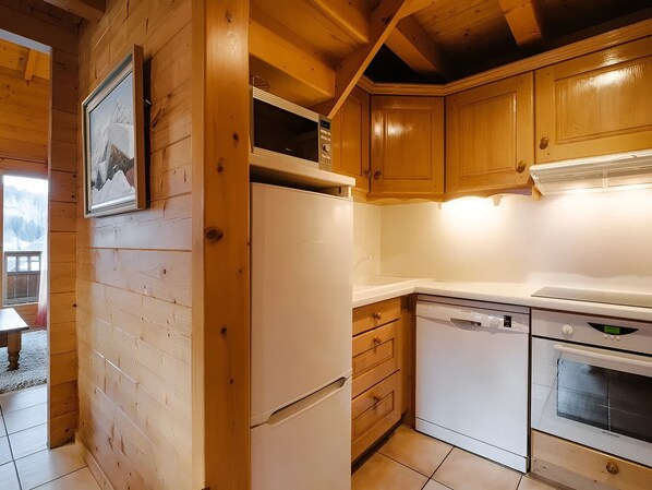 A wooden cabin interior with a refrigerator, dishwasher, oven, and wooden cabinets.