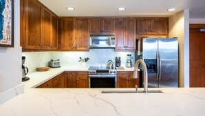 Une cuisine moderne avec des meubles en bois, des appareils en acier inoxydable et un plan de travail en marbre.