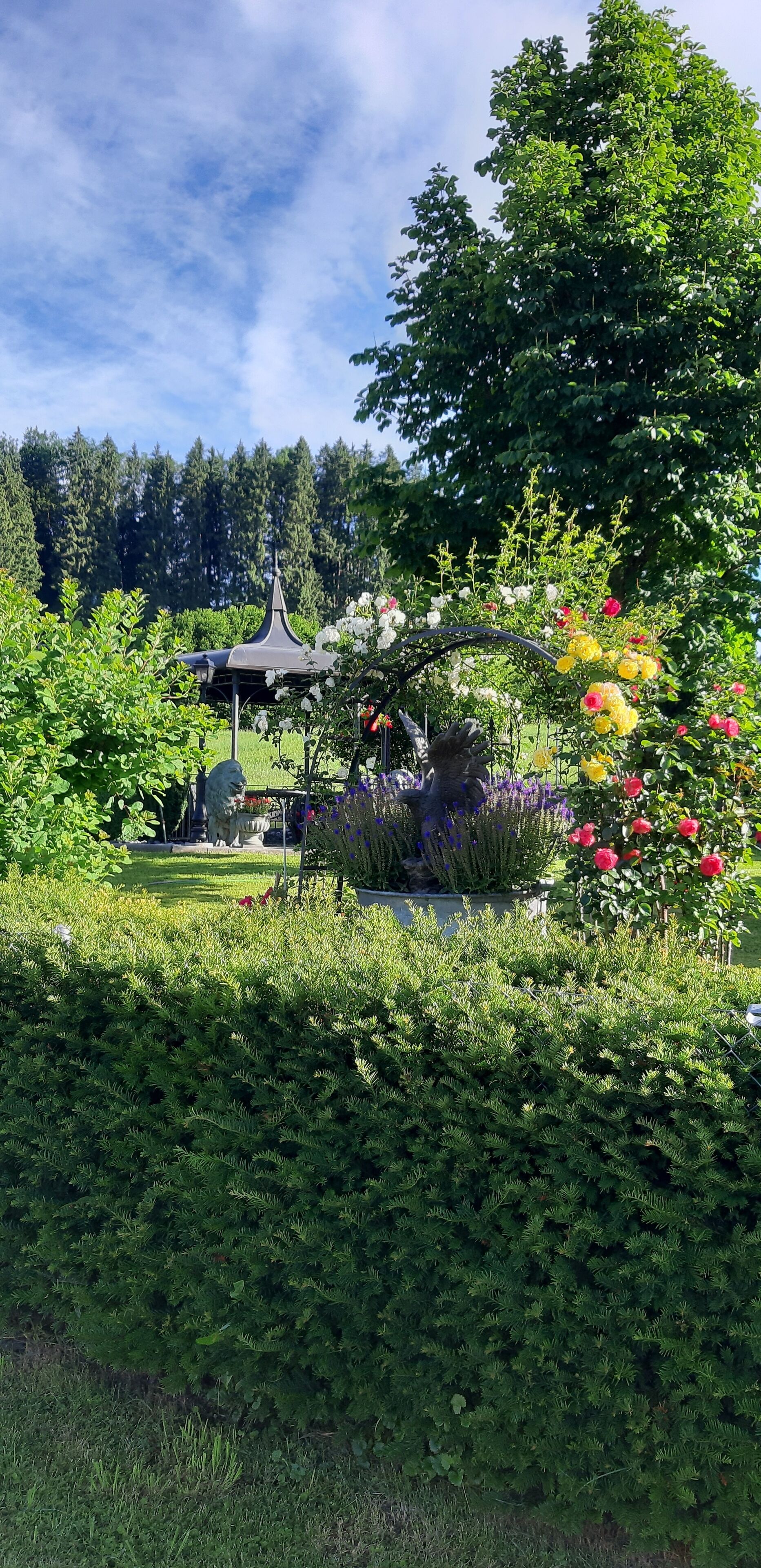 Ein Garten mit einem Pavillon, verschiedenen Pflanzen und einer Statue.