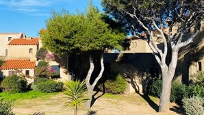 A building with a tiled roof, surrounded by trees and shrubs. - Nice 2-room Apt, 4 people, Lumio, AC, parking (Lumio)