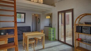 A spacious living area with a wooden dining table, a sofa, and a kitchen in the background. - Nice 2-room Apt, 4 people, Lumio, AC, parking (Lumio)