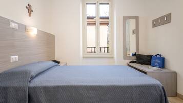 Un dormitorio con cama, mesita de noche, espejo y ventana.