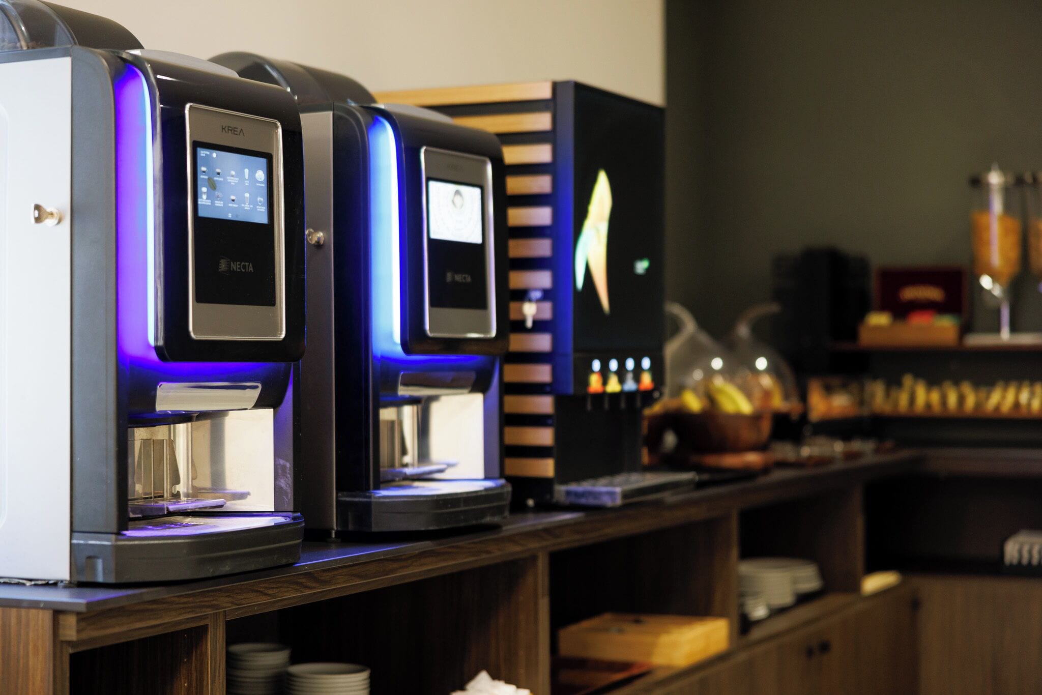 A row of coffee machines with digital displays, a coffee grinder, and a beverage dispenser.
