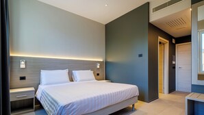 A modern hotel room with a large bed, bedside tables, and a built-in headboard with ambient lighting. - Casa San Giuseppe (Rome)