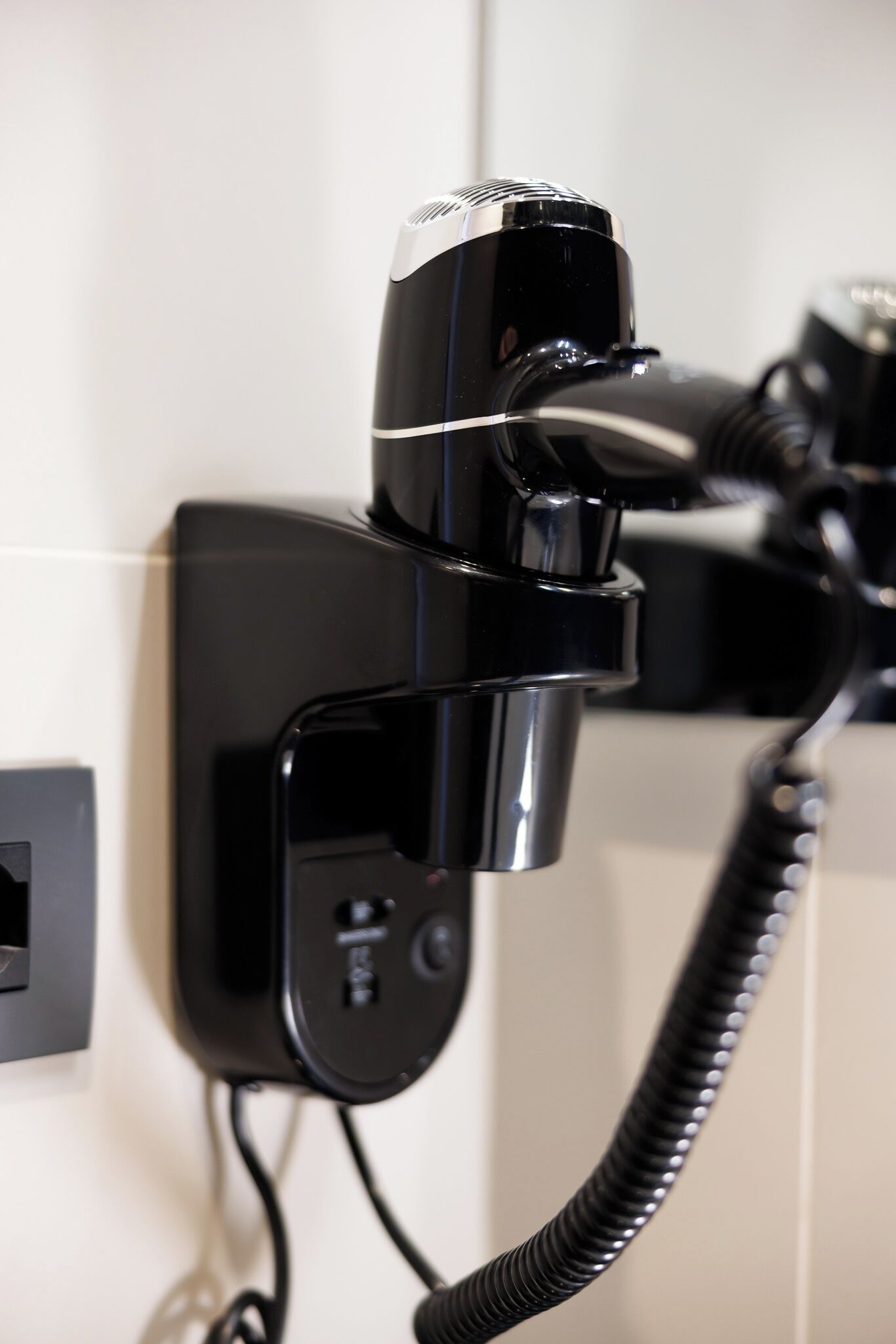 Een haardroger bevestigd aan een muur, aangesloten op een stopcontact.
