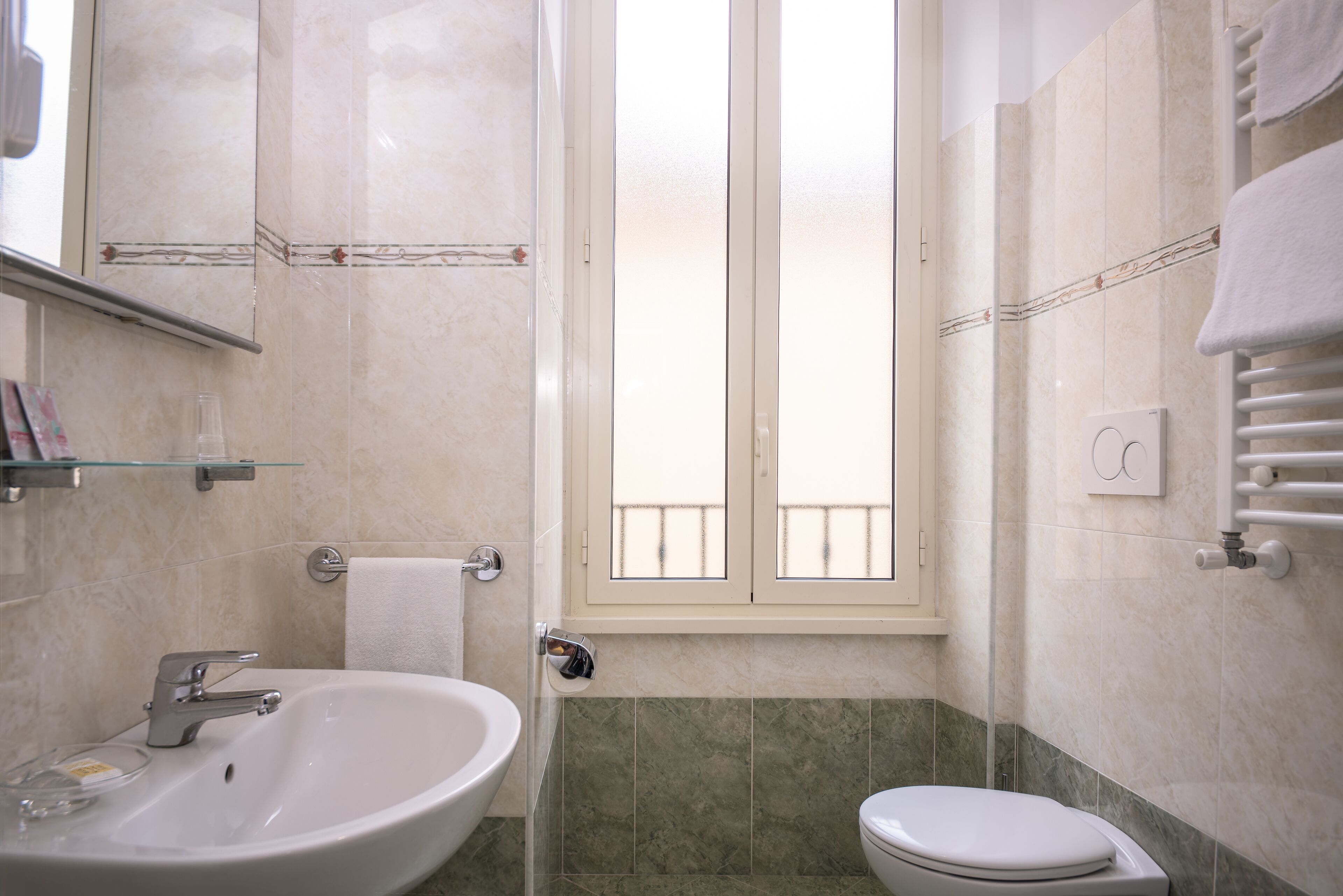 A bathroom with a sink, toilet, and a window with a view of a balcony.