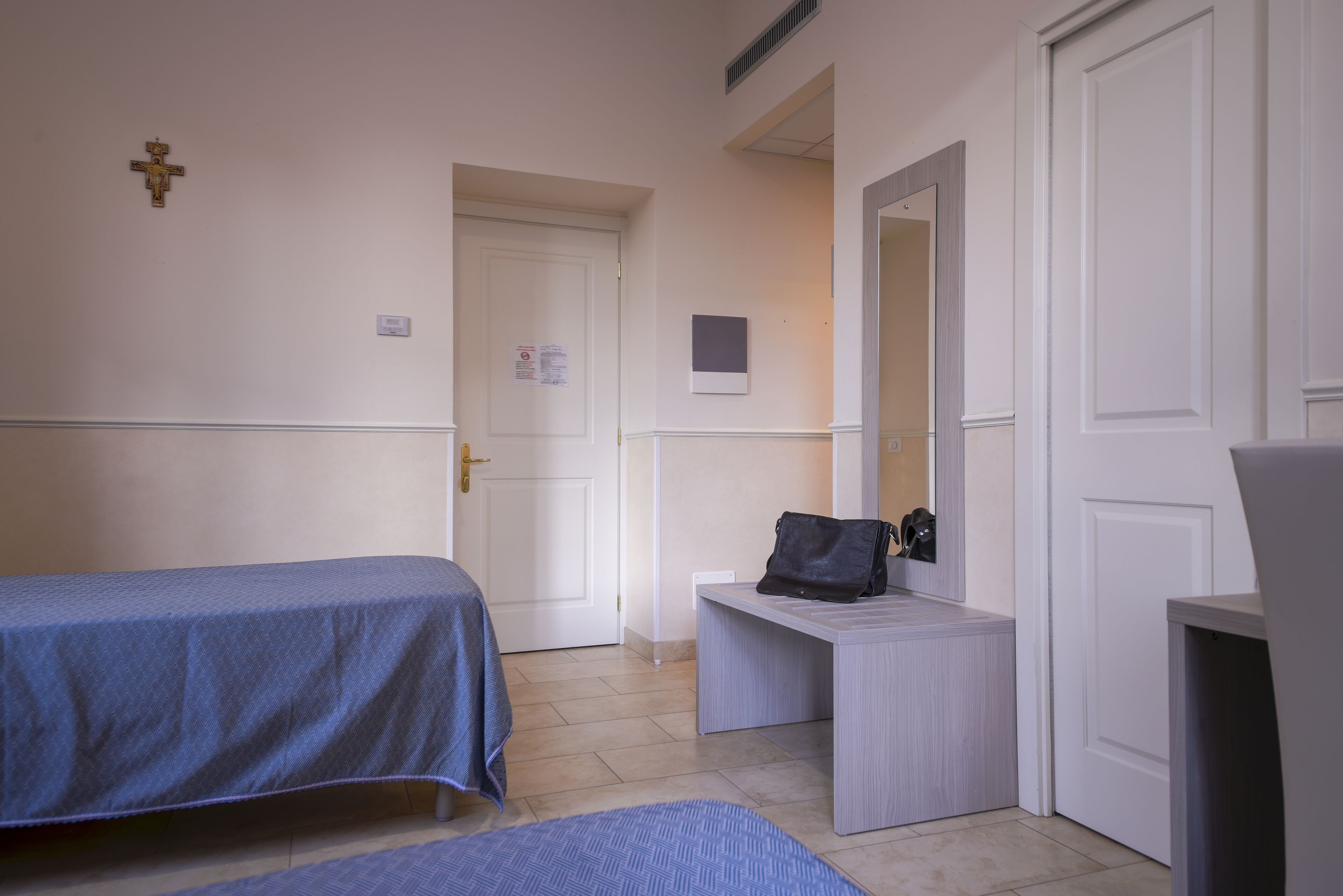 Una habitación de hotel con una cama, una mesita, una silla, un escritorio y una puerta.