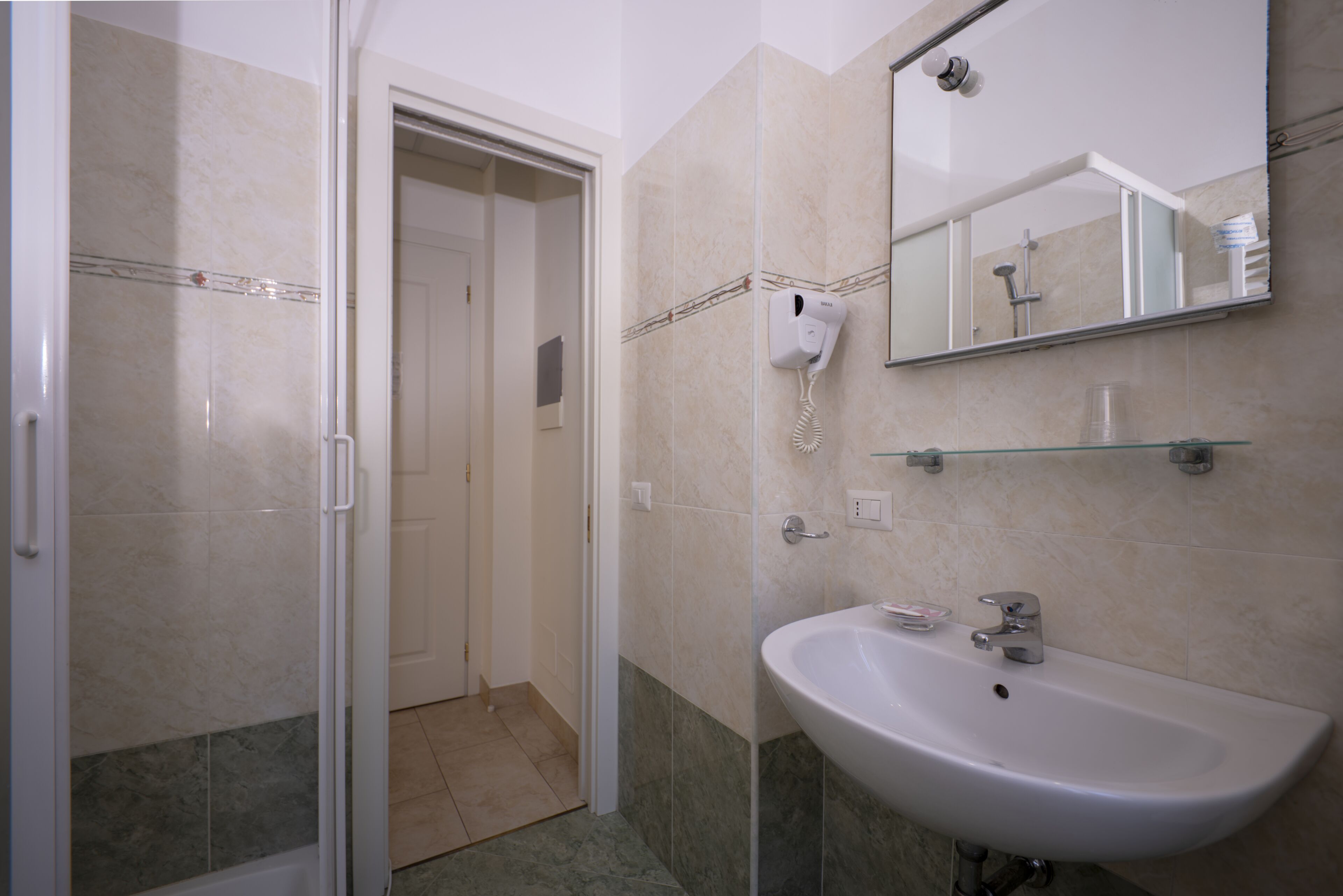 Un baño con lavamanos, espejo y cabina de ducha de vidrio.