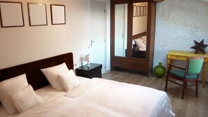 Een slaapkamer met een groot bed, een nachtkastje met een lamp, een stoel en een spiegel.