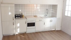 Een moderne keuken met witte kasten, een ingebouwde oven, een spoelbak en een broodrooster.