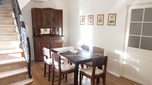 Een eetgedeelte met een houten tafel en stoelen, een houten kast en een trap.
