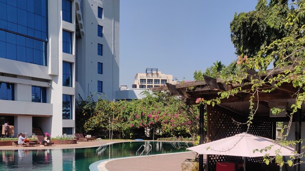A swimming pool with a curved edge, surrounded by lounge chairs and a shaded area with a 'SINGER' sign. - Seagull Hotels Ltd. (Cox's Bazar)