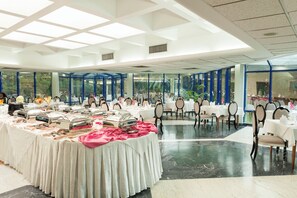 Een ruime binnentuin voor evenementen met gedekte tafels voor een formeel diner, met een modern plafond en grote ramen.