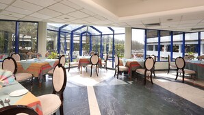 A spacious dining area with multiple tables and chairs, large windows, and a modern architectural design. - Seagull Hotels Ltd. (Cox's Bazar)