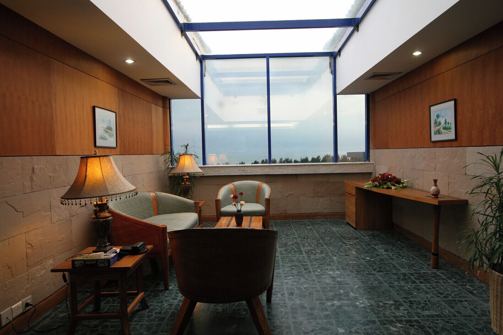A cozy room with a skylight, wooden walls, a comfortable chair, a small table, and a view of the outdoors.