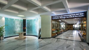 A spacious lobby with a marble floor, a glass wall with a mosaic pattern, and a sign indicating amenities like a shopping arcade, swimming pool, spa, gymnasium, massage, bar, and live music. - Seagull Hotels Ltd. (Cox's Bazar)
