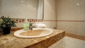 Ein Badezimmer mit Waschbecken, Dusche und einer Topfpflanze.