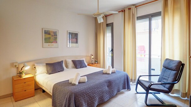 Ein Hotelzimmer mit Bett, Stuhl, Nachttisch, Lampe und zwei Wandbildern.