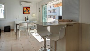 A modern kitchen with a central island, white chairs, and a dining table. - Balmins White by Hello Homes Sitges (Sitges)