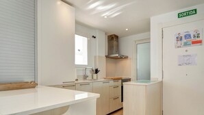 A modern kitchen with white cabinetry, a built-in oven, and a stainless steel range hood. - Balmins White by Hello Homes Sitges (Sitges)