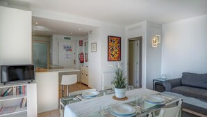 A modern living room with a dining area, a sofa, a TV, and a bookshelf. - Balmins White by Hello Homes Sitges (Sitges)