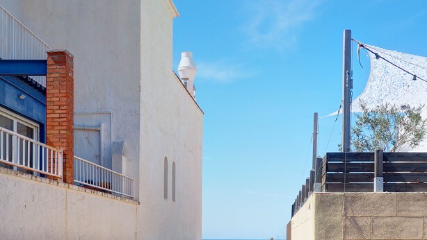 A coastal building with a balcony, a white facade, and a view of the sea. - Barco Attic by Hello Homes Sitges (Sitges)