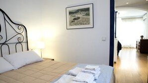 A neatly made bed with a quilted headboard, a framed picture on the wall, and a lamp beside it. - Barco Attic by Hello Homes Sitges (Sitges)