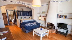 A cozy living room with a sofa, a coffee table, and a fireplace. - Barco Attic by Hello Homes Sitges (Sitges)